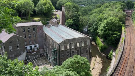 View-looking-down-onto-historic-old-mills-with-railway-tracks-to-the-right-and-all-surrounded-by-woodland-blowing-in-the-breeze