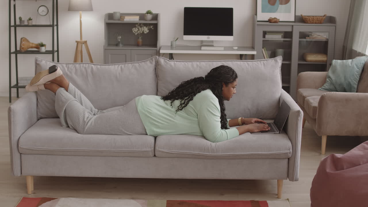 African-American Businesswoman Lying on Sofa with Laptop