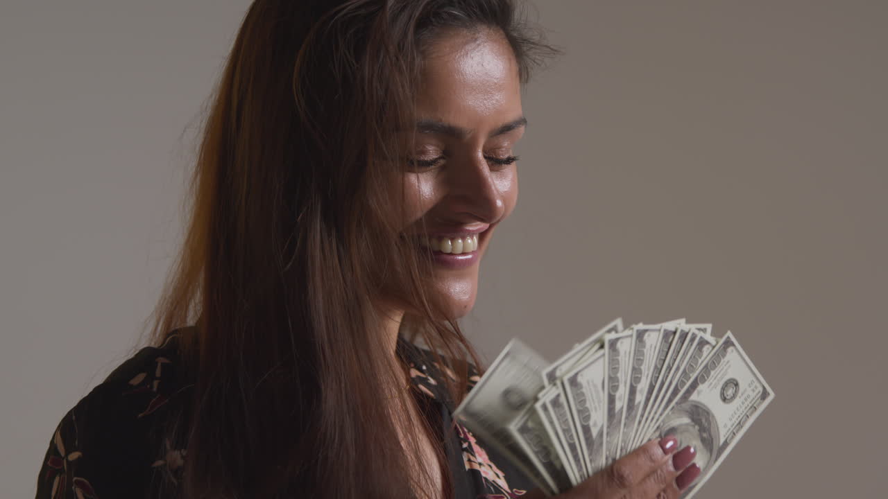 Studio Shot Of Excited Woman Celebrating Winning Cash Prize Holding Handful Of 100 Dollar Bills 1