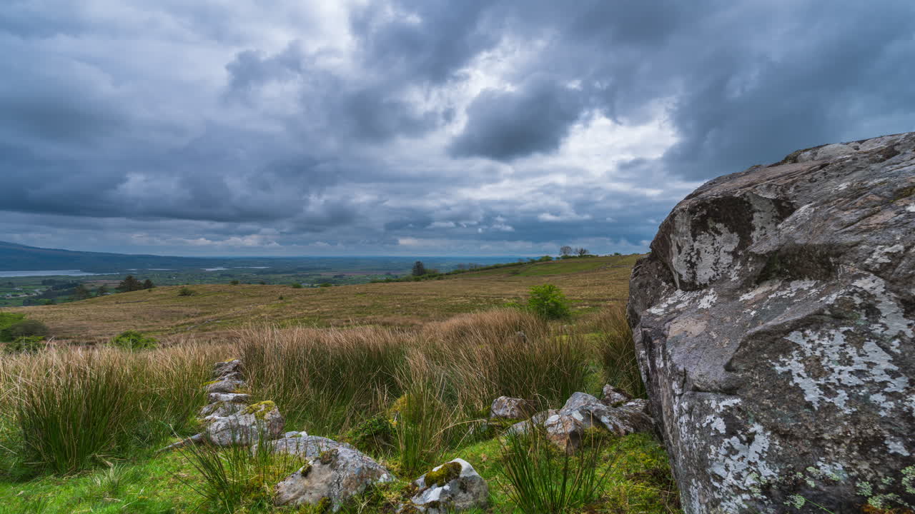 Time lapse of rural landscape with rocky foreground hillside and lake in the distance during a spring sunny cloudy day in Arigna mountains in county Leitrim in Ireland