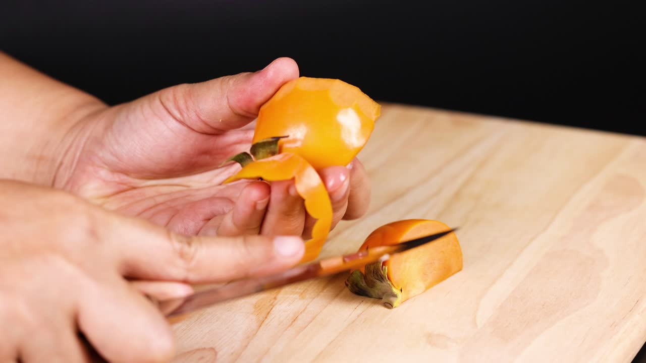 Hænder skræller omhyggeligt en moden persimmon