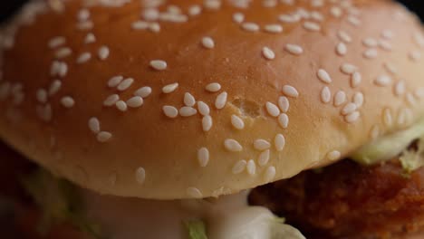 Los-Dedos-Recogen-Semillas-De-Sésamo-Del-Pan-De-Hamburguesa-De-Pollo-Frito,-Primer-Plano