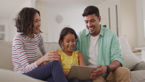 Felices-Padres-Hispanos-E-Hija-Sentados-En-El-Sofá-Usando-Una-Computadora-Portátil