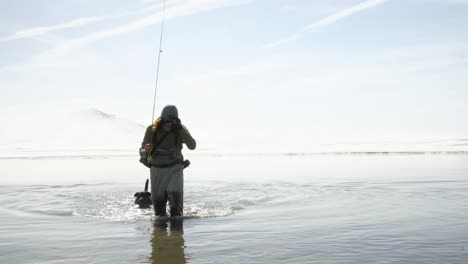 high key nature scene: fisherman and dog in pale blue mountain lake