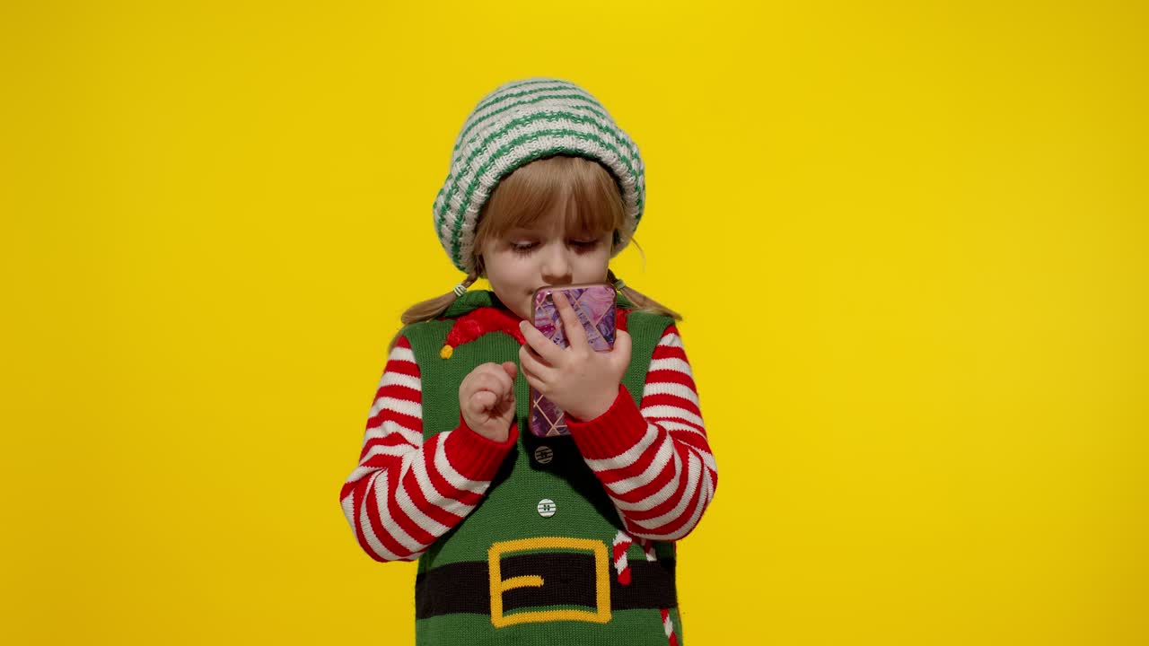 Dívka, vánoční skřítek a pomocník Santy, něco píše na mobilním telefonu a baví ji prohlížení sociálních sítí