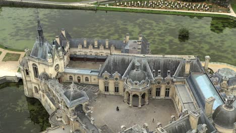 wide aerial establishing shot of historic chateau de chantilly and grounds, france. famous french castle, travel destination, european heritage