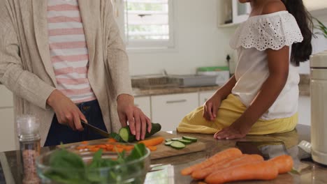 Hispanic-father-teaching-daughter-sitting-on-countertop-cooking