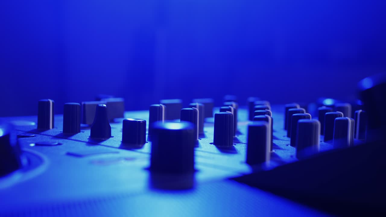 DJ Mixer Controls Under Neon Lights