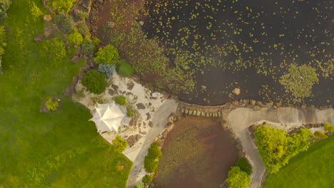 aerial view smoothly moves forward, showing a calm lake with nearby modern structure