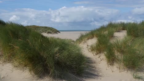 día ventoso en la playa de barmouth, dunas de arena vacías mirando hacia la península de llyn, gales, reino unido versión de 10 segundos