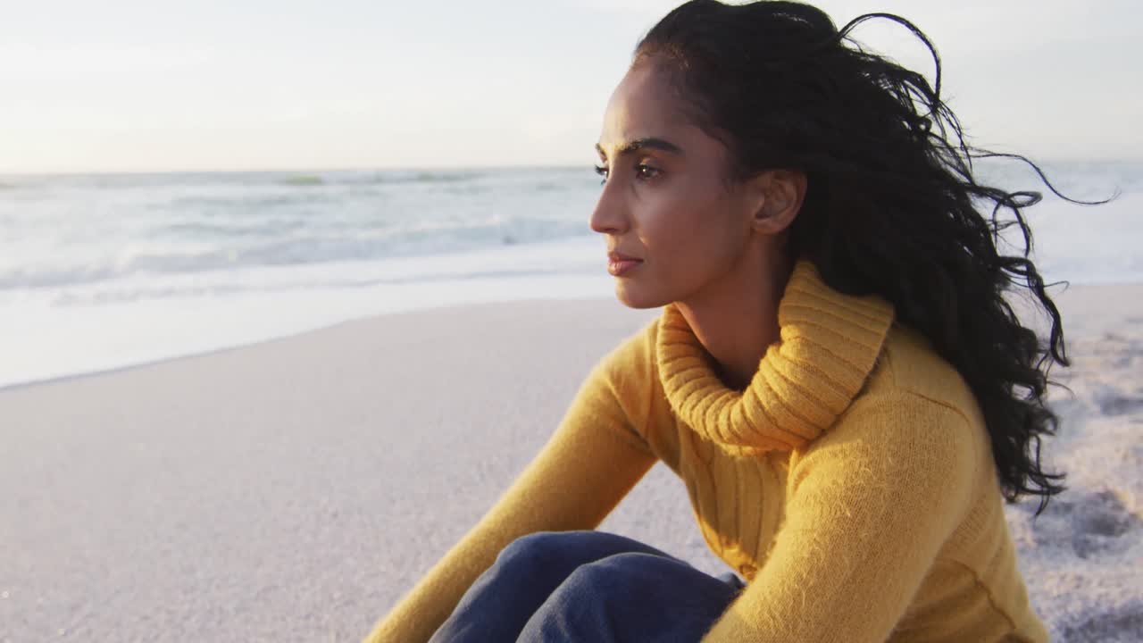 retrato de una mujer hispana pensativa sentada en la playa al atardecer