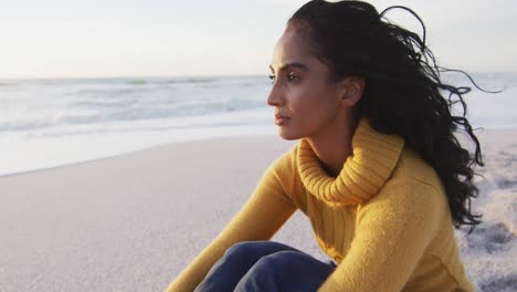 retrato de una mujer hispana pensativa sentada en la playa al atardecer