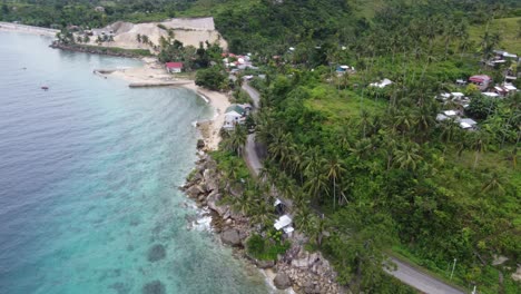 Tuk-tuk-driving-along-tropical-coastal-road-at-lush-green-overgrown-seaside-foothill-on-Cebu-island,-Philippines