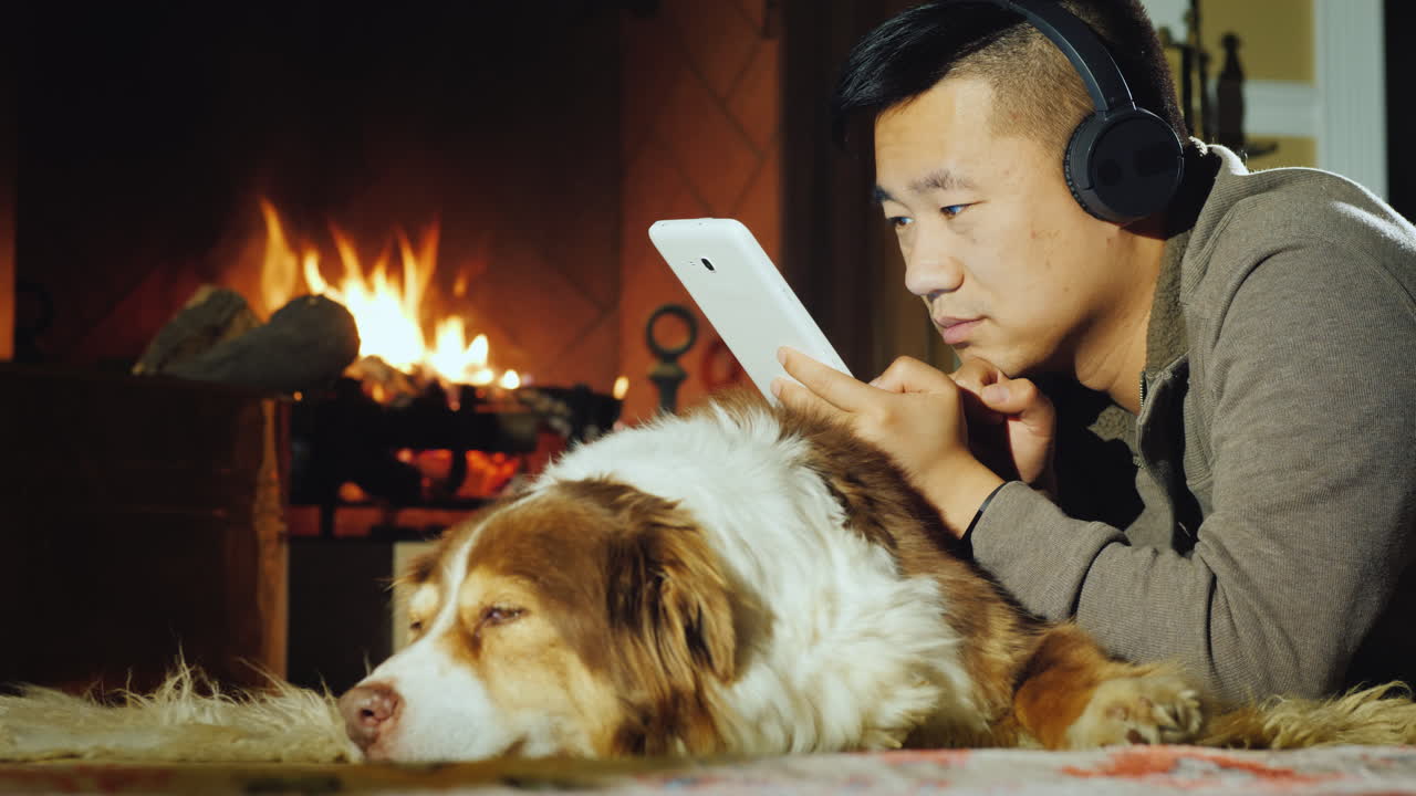 아시아 남자는 벽난로 근처에 태블릿을 사용합니다 02