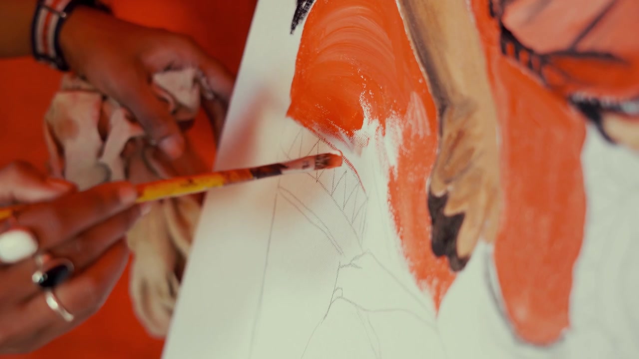 Zoom in shot of asian artist painting with paintbrush on colorful picture