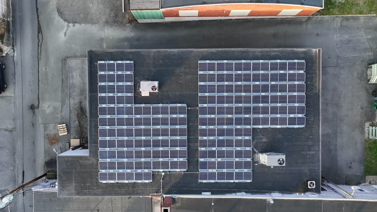 해가 지는 작은 지역 사회의 산업 건물 꼭대기에 태양 전지판과 에어컨 단위가 내려오는 공중 뷰