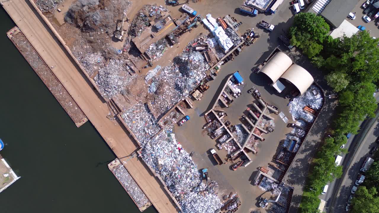 metal scrap yard, showing workers sorting and managing waste materials for recycling purposes near a city. Unique aerial view flight vertical bird's eye view drone