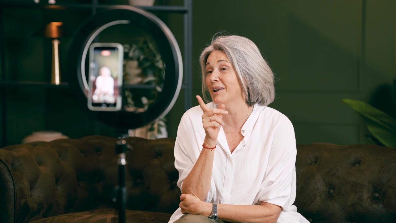 Donna matura che registra contenuti video con lo smartphone e una luce ad anello