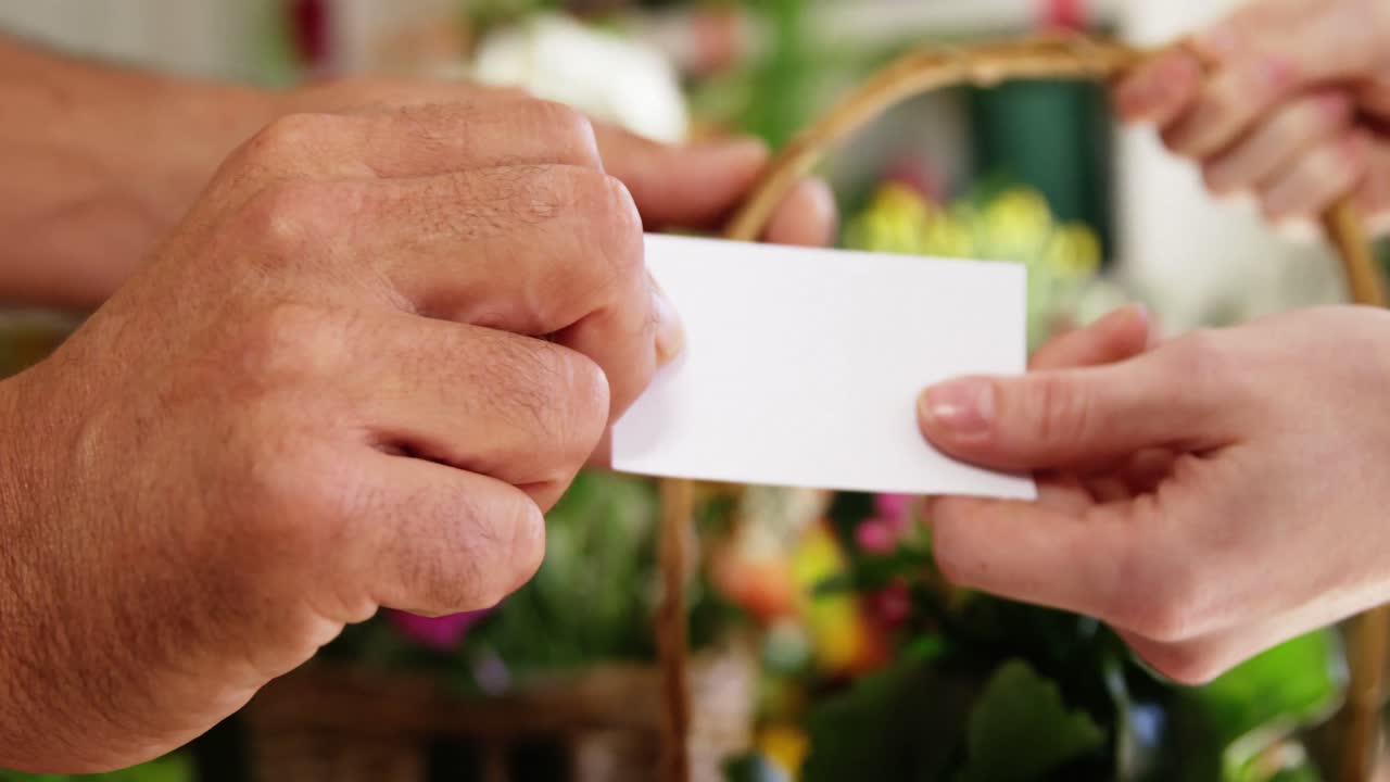 florista dando tarjeta de visita y canasta de flores al cliente en la tienda de flores