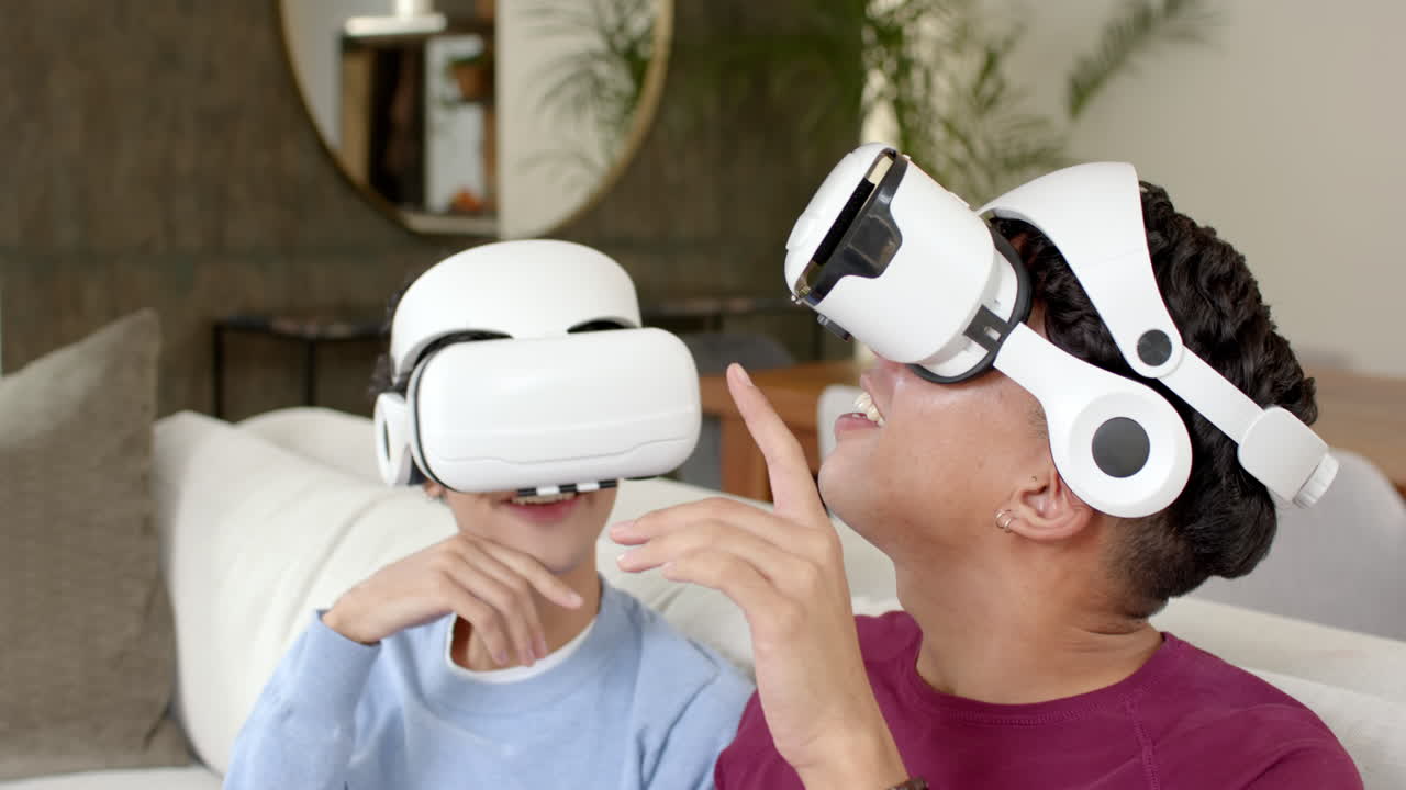 Using VR headsets, multiracial gay couple enjoying virtual reality experience at home