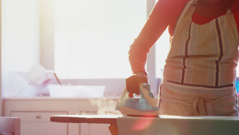 woman ironing shirt on ironing board in kitchen 4k