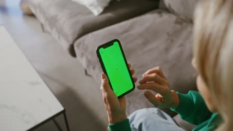 woman using a smartphone with a green screen