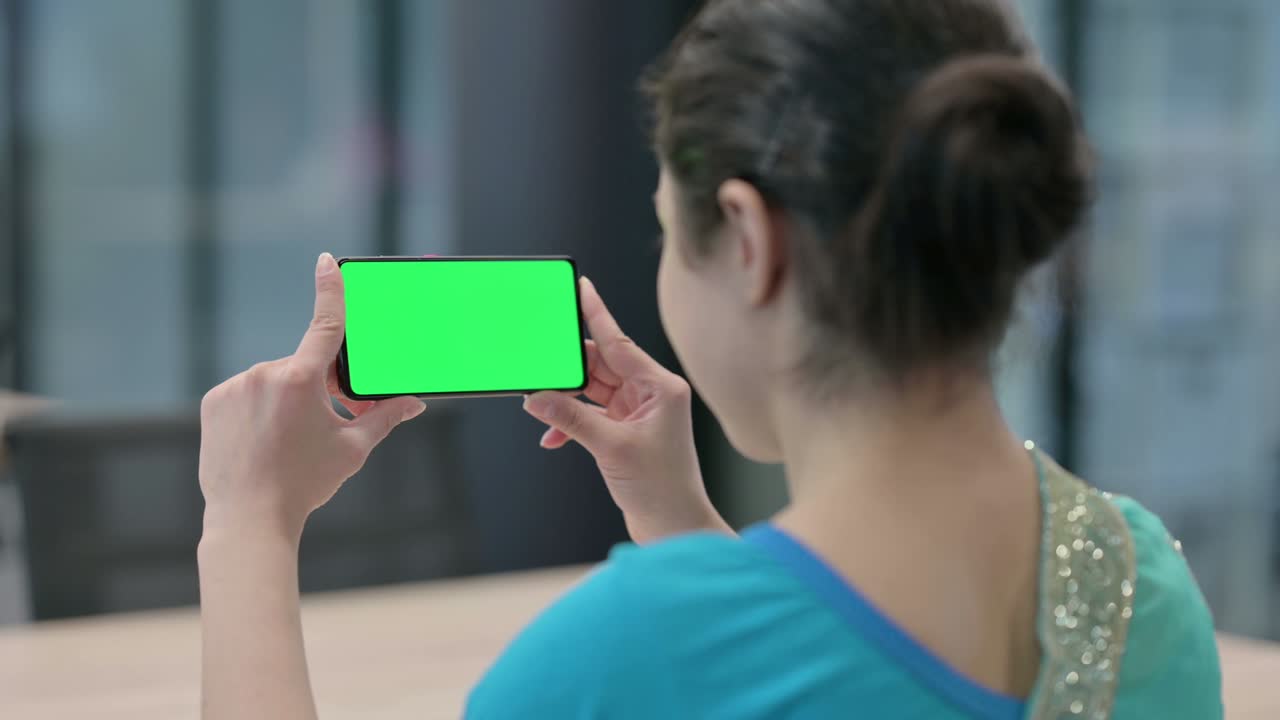 인디언 여성이 크로마 키 스크린으로 스마트폰을 보고 있습니다.