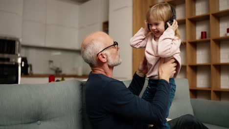niña bailando en casa con su abuelo mientras escucha música en los auriculares