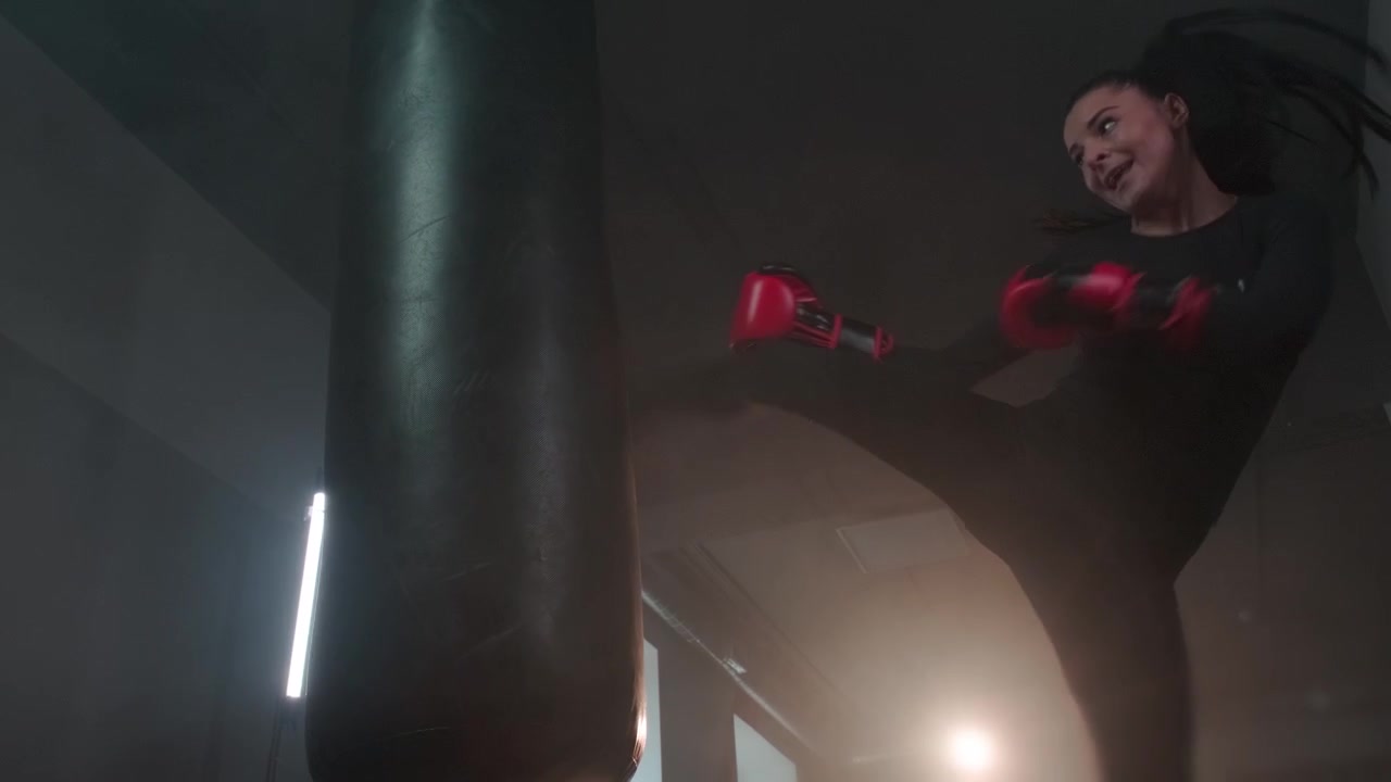 Jovem Mulher Treinando Kickboxing com Saco de Pancadas na Academia