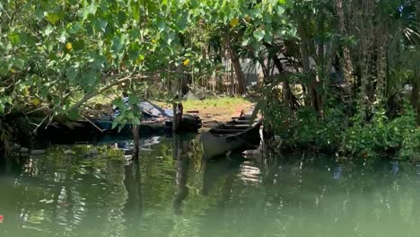 4k video of a lush green riverbank passing a parked boat and a private home