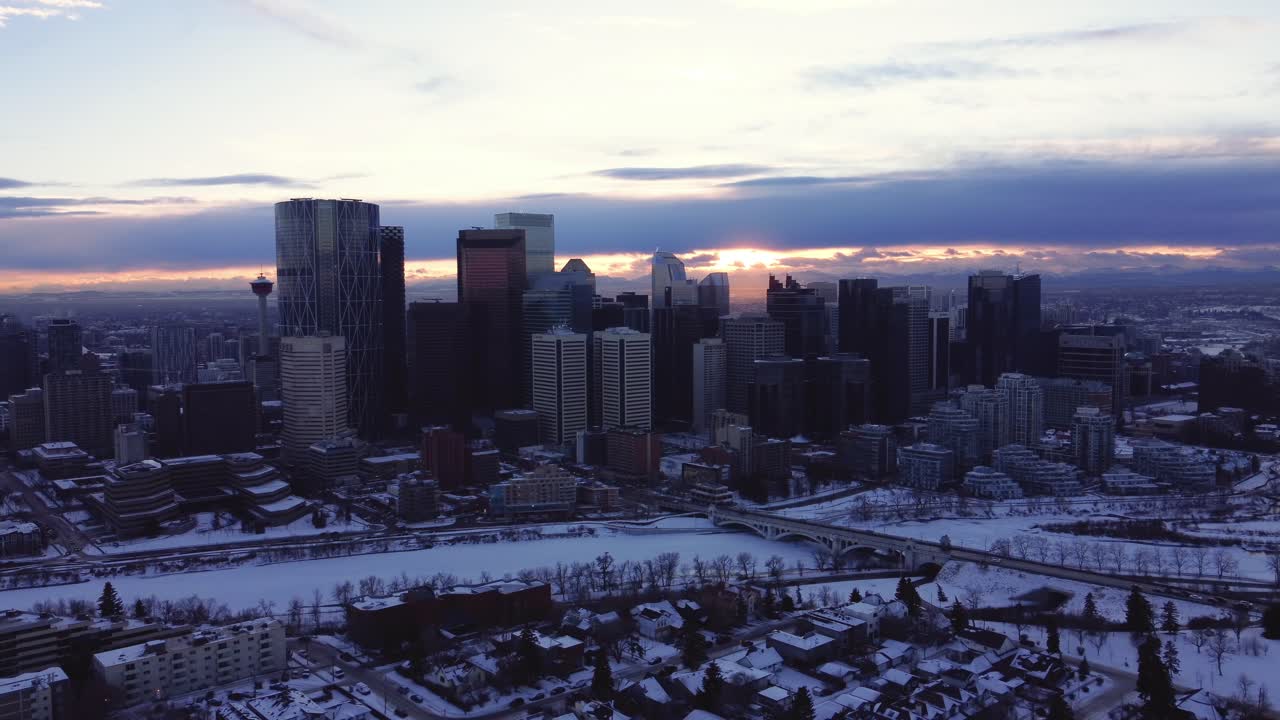 volando a través del horizonte del centro de calgary con un dron al atardecer durante el invierno