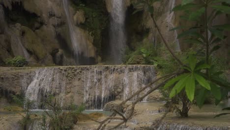 Clip-De-Cámara-Lenta-En-Una-Pequeña-Cascada-Con-Hojas-Verdes-Frente-A-La-Cámara