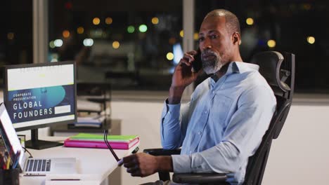 Professional-businessman-talking-on-his-phone-while-sitting-on-his-desk-in-modern-office-in-slow-mot