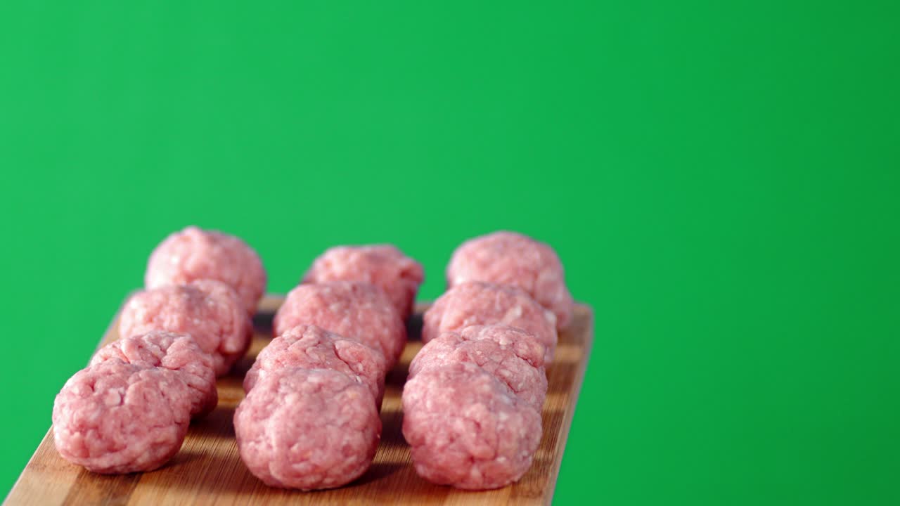 las albóndigas crudas en una tabla de cortar de madera giran lentamente.
