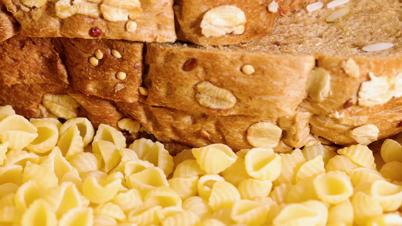 Whole wheat bread and conchiglie pasta arranged together in warm lighting. Close-up view highlights textures and colors