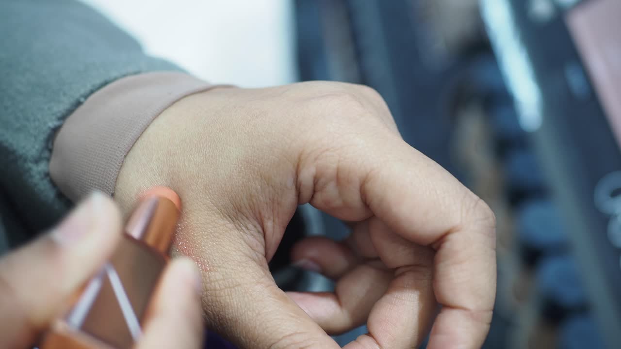 mujer aplicando lápiz labial en su mano