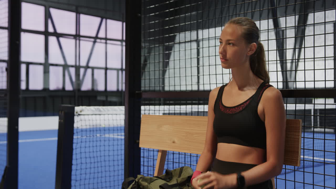 Woman holding coffee cup, preparing for padel tennis match with teammate, on indoor court