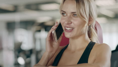 Schöne-Frau,-Die-Im-Fitnessstudio-Mit-Dem-Smartphone-Spricht.-Lächelndes-Mädchen,-Das-Pause-Macht