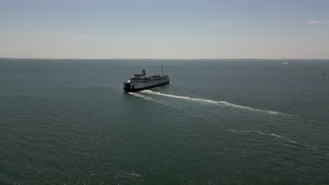 An-aerial-view-of-a-large-white-ferry-leaving-the-terminal-out-on-Long-Island,-NY-on-a-sunny-day