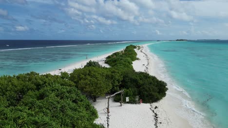 long sandbank of dhigura island in the maldives with natural shade of lush tropical vegetation and white sand beach