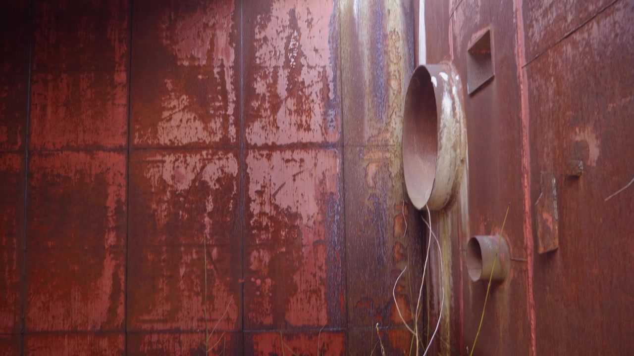 Interior view of an abandoned silo in Moldova, showing heavily rusted metal walls, circular openings and decayed industrial structures with a dark Cold War atmosphere.