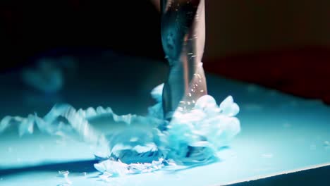 an extreme close-up, slow-motion shot shows a metal drill bit boring a hole into a sheet of blue plastic, sending beautiful curly shavings spiraling upwards from the surface