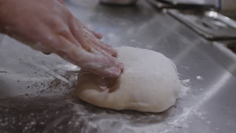 forming by hand neapolitan pizza ball dough into the circle on cooking table in pizzeria