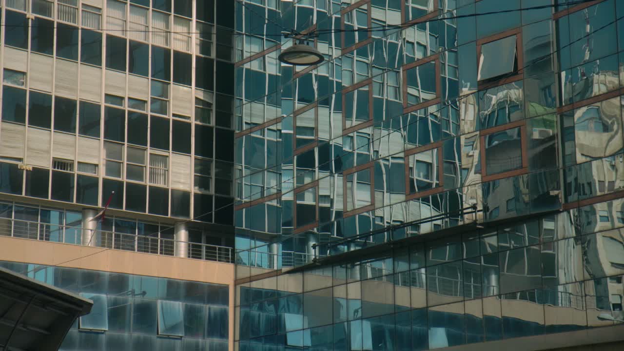 Modern city glass facade with reflections of surrounding buildings. The modern and old complex grid of windows creates an abstract view, blending reflections and architecture.