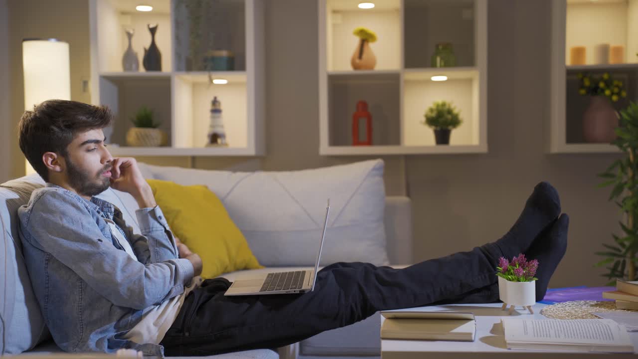 Man watching movie on laptop at night at home.