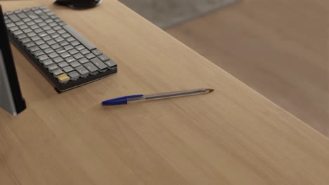 3d animation of a blue bic pen on a home desk next to a computer