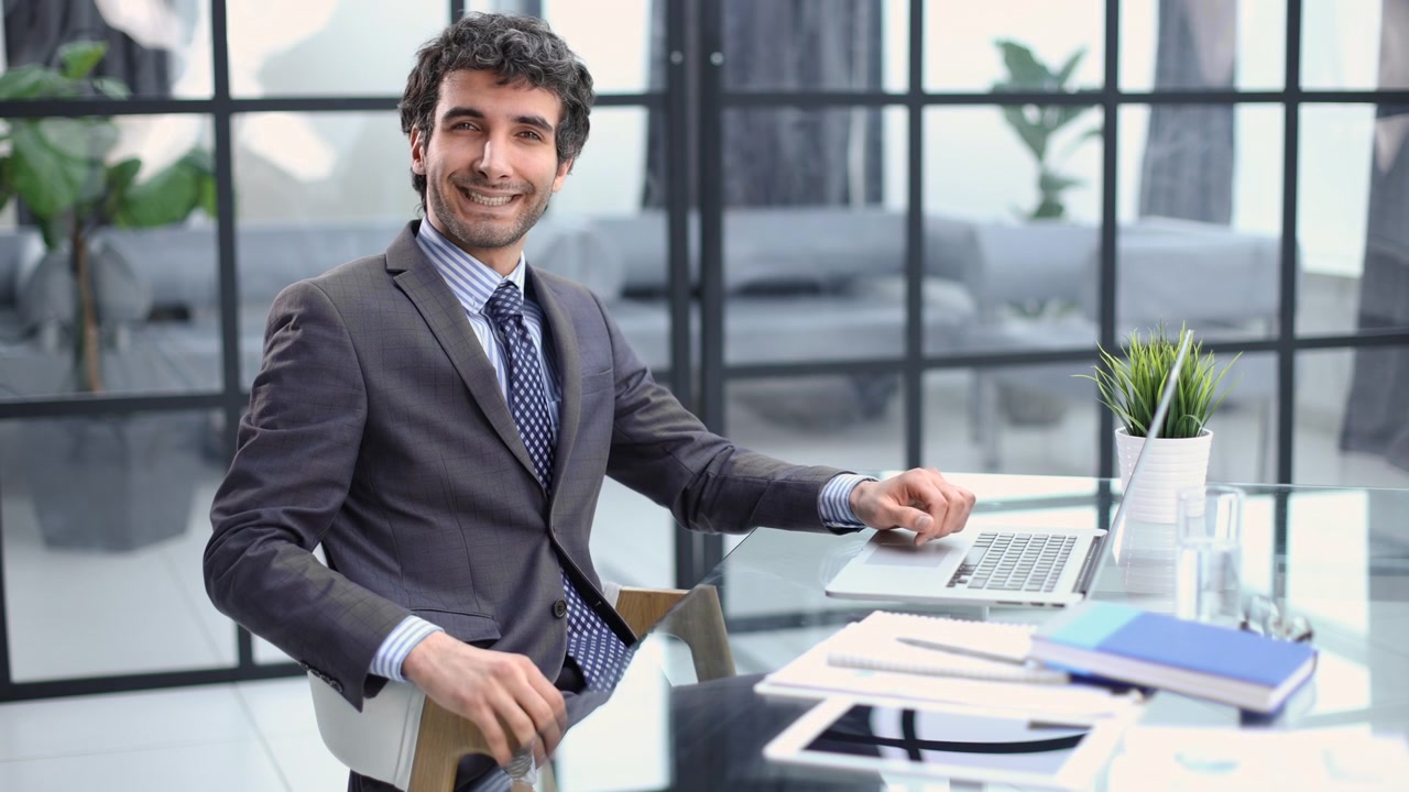 Uomo d'affari che lavora al laptop e sorride in un ufficio moderno