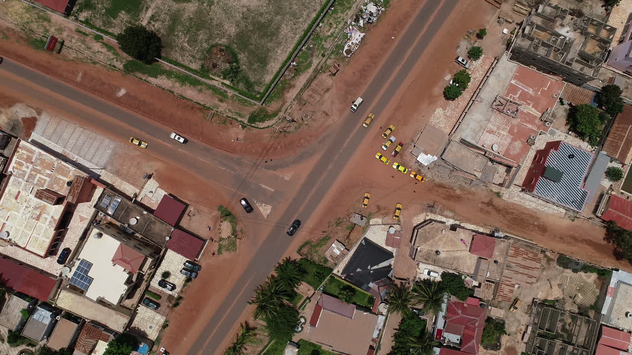 Vista aerea con drone a volo d'uccello dell'incrocio a T su Kololi Road a Serrekunda, Gambia, Africa, con traffico in movimento e auto