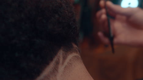 Amazing-slow-motion-shot-of-a-detail-shot-of-a-haircut-by-a-professional-barber-in-a-barbershop-making-a-design-with-a-razor-to-a-young-afro-man-during-the-afternoon