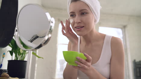 mujer aplicando mascarilla facial